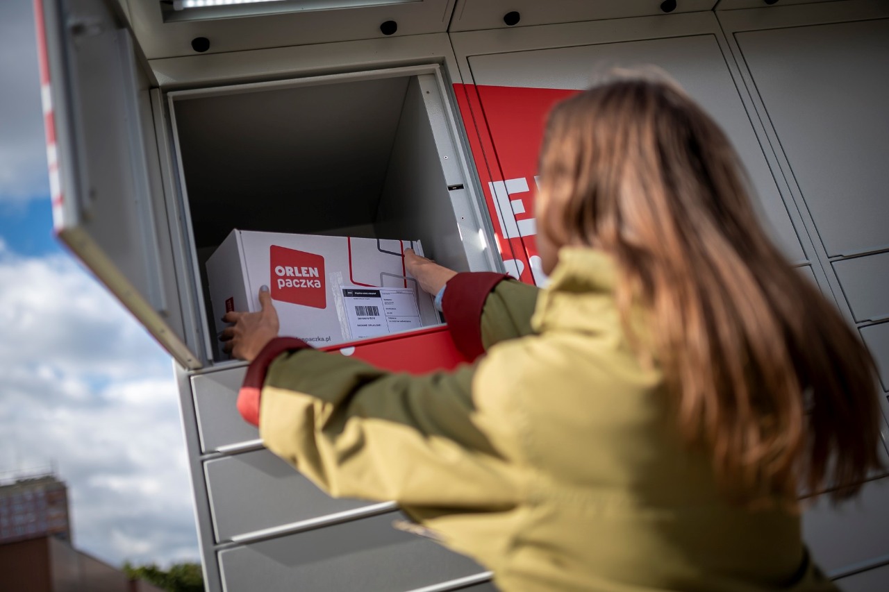 Automat paczkowy ORLEN. Kobieta wkładająca przesyłkę do automatu paczkowego ORLEN Paczka.