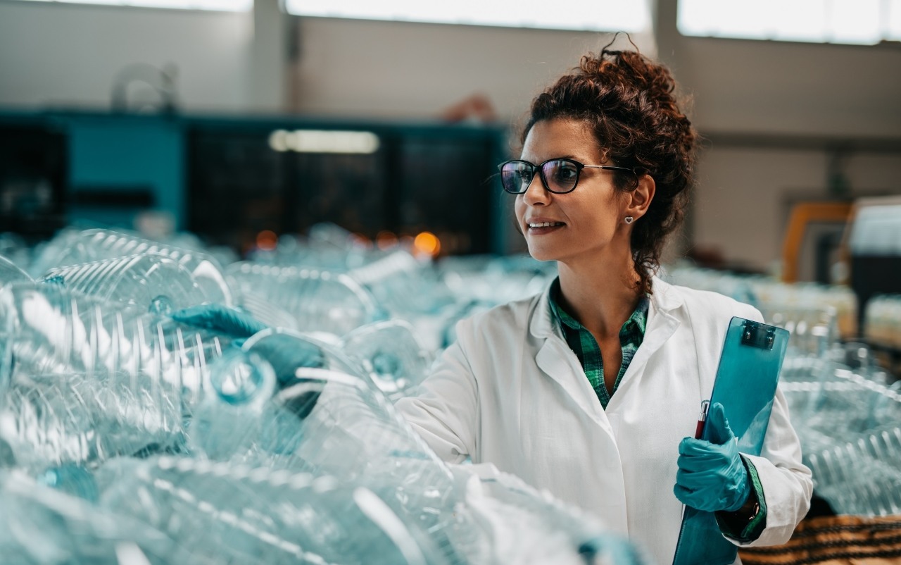 Young happy female worker in bottling factory recycling department. Inspection quality control.