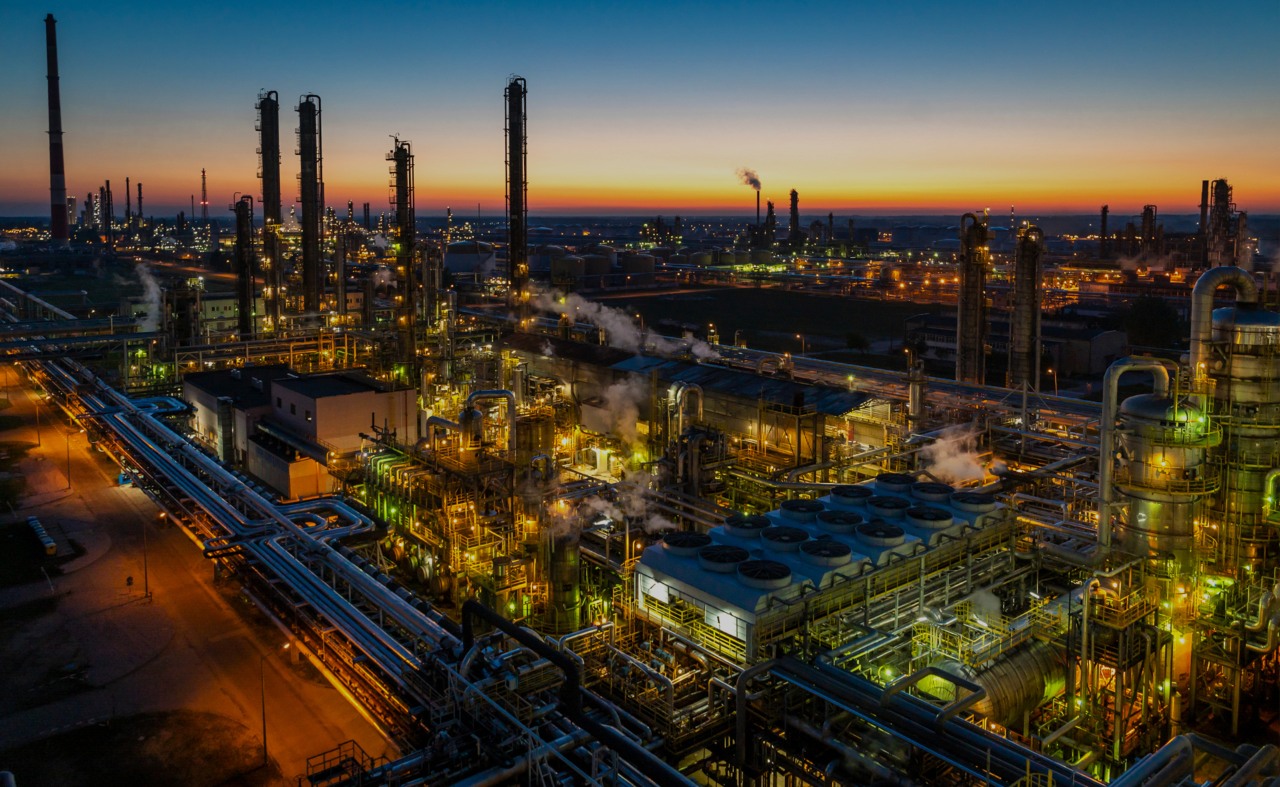 ORLEN petrochemia i produkty petrochemiczne. Kompleks rafineryjny oświetlony nocą, z licznymi wieżami destylacyjnymi, zbiornikami i systemami rurociągów. 