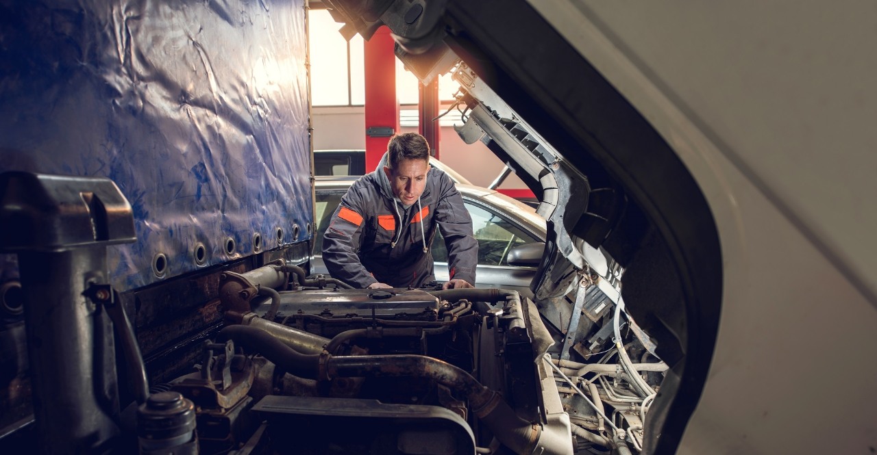 Auto mechanic working on a truck in a repair shop.