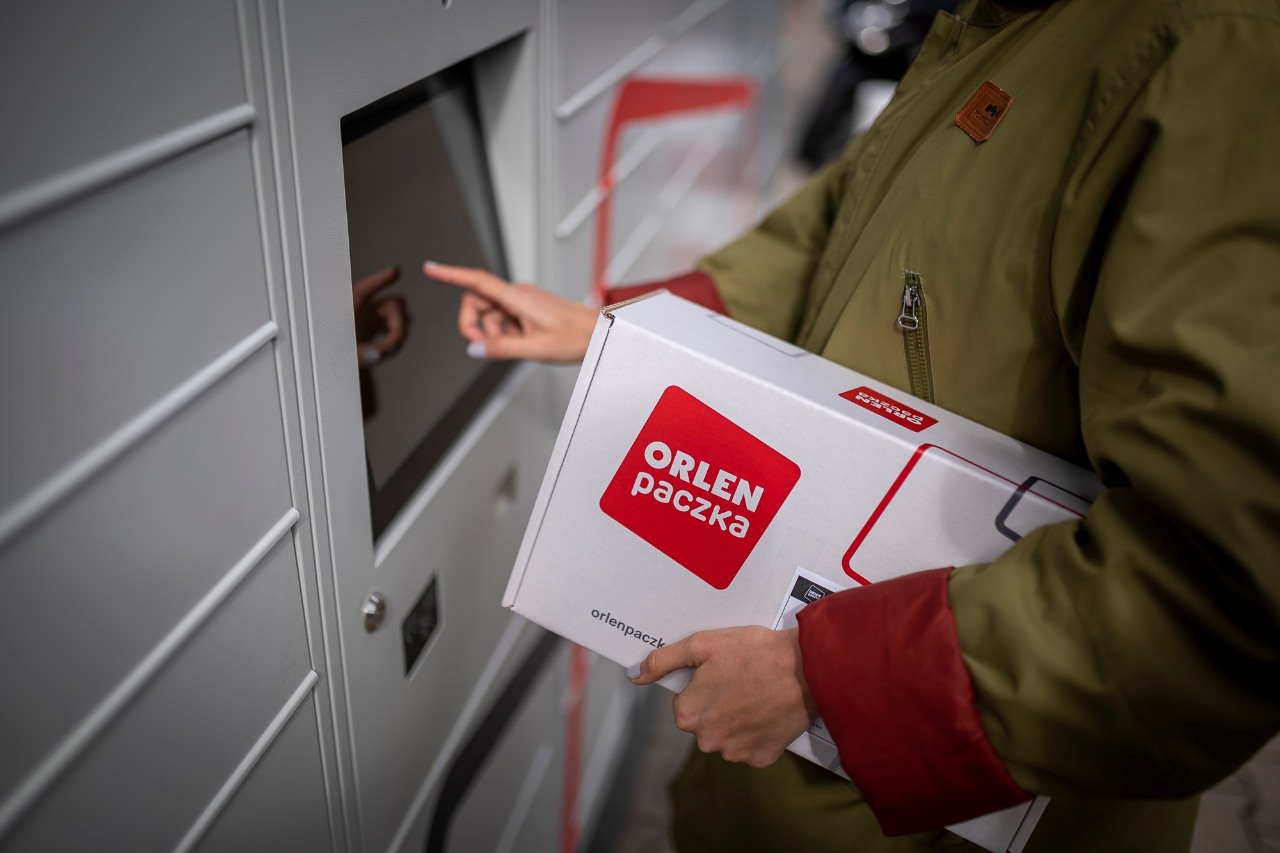 Automaty paczkowe ORLEN paczka. Kobieta nadająca przesyłkę w automacie paczkowym ORLEN paczka.