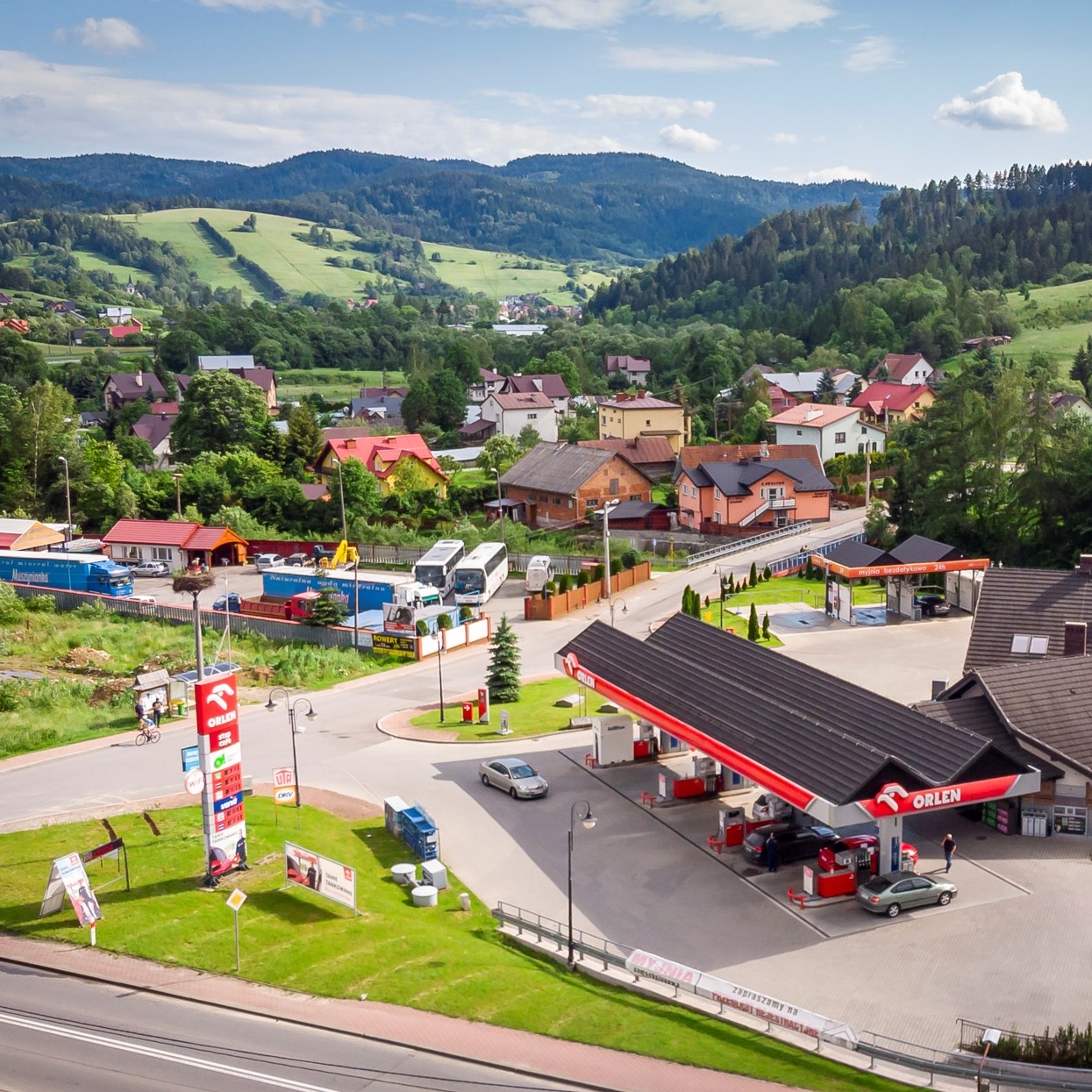 ORLEN Stop Cafe i stacje ORLEN. Stacja paliw ORLEN w Krynicy-Zdrój, otoczona drzewami i widokiem na góry w tle. 