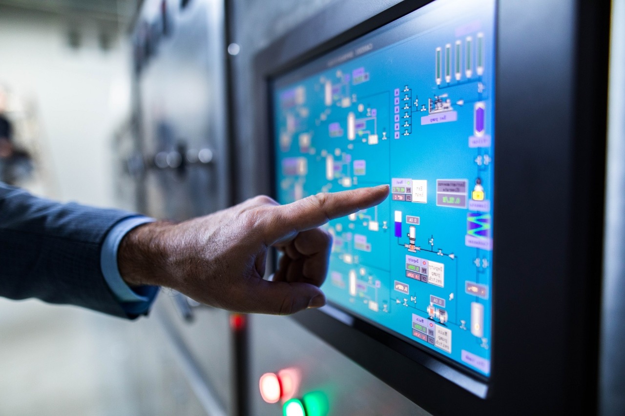 Close up of unrecognizable inspector aiming at data on a machine in a factory.