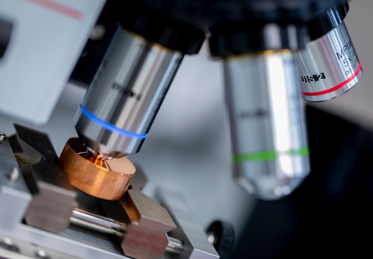 Innowacje i R&D – Grupa ORLEN. Metalowy przedmiot pod mikroskopem w trakcie badania laboratoryjnego.  