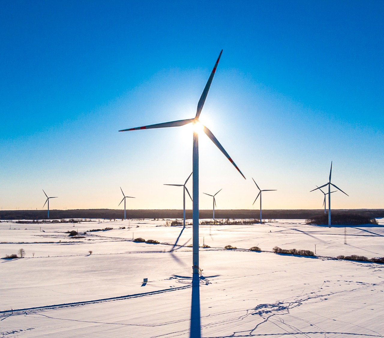 Źródła energii odnawialnej i transformacja energetyczna - Grupa ORLEN. Wiatraki w zimowej scenerii pracujące nad wytwarzaniem energii odnawialnej.