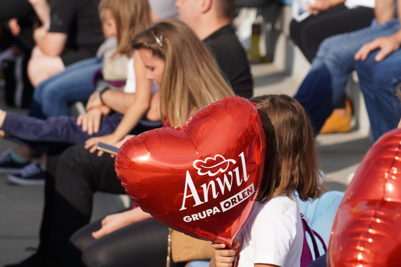 Dziecko trzymające balona w kształcie serca z logo ANWIL, podczas imprezy plenerowej.
