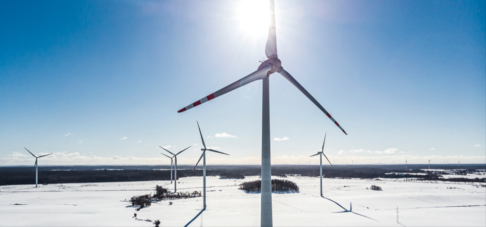 Cele zrównoważonego rozwoju ORLEN. Wiatraki w zimowej scenerii pracujące nad wytwarzaniem energii odnawialnej.