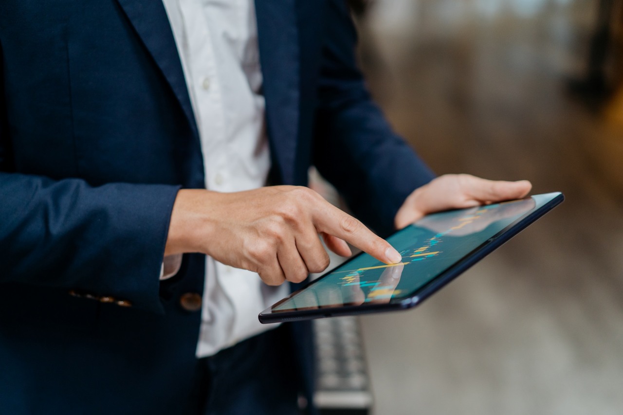 Image of an Asian businessman checking stock market chart on digital tablet. Fund manager looking at stock market chart on digital tablet.